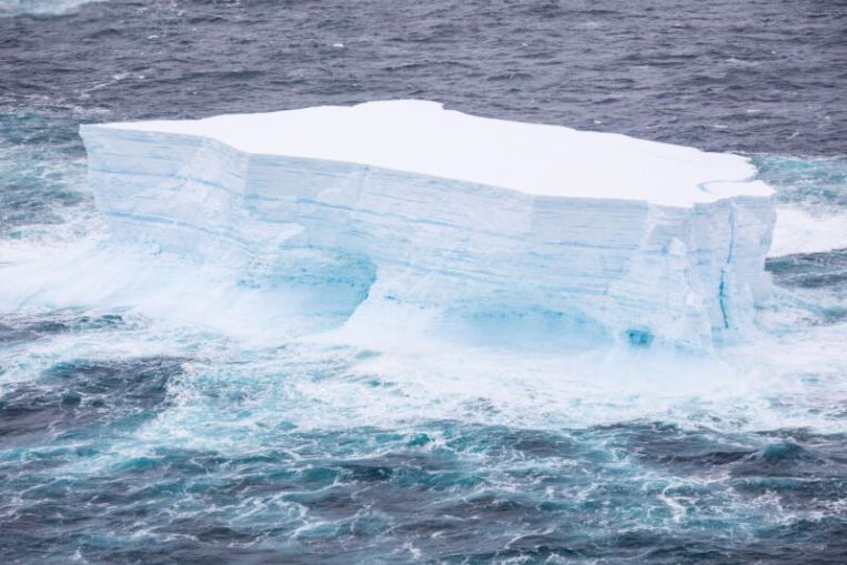 Fuertes corrientes giran alrededor de un enorme iceberg, provocando que se rompa al acercarse a la isla de pingüinos del Atlántico Sur.