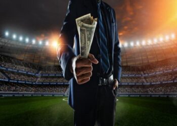 Hombre en campo de futbol con dinero en la mano