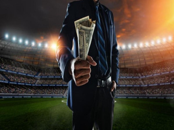 Hombre en campo de futbol con dinero en la mano