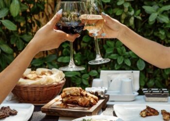 Chicas brindando con vino en una mesa con comida de restaurante